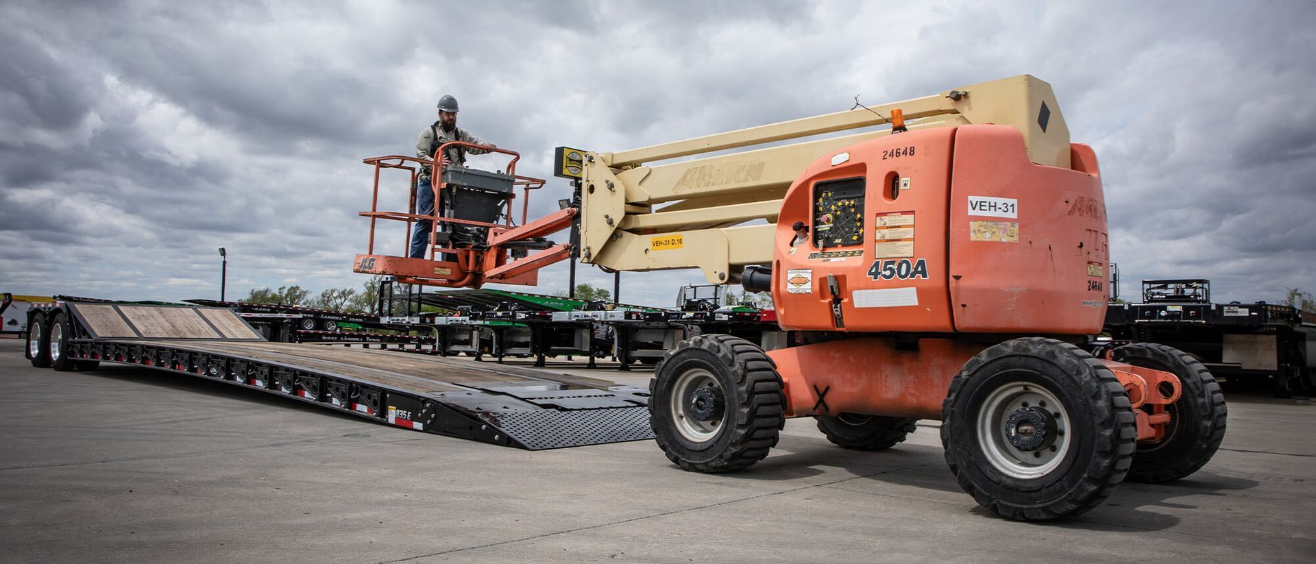 A man is standing on a lift on top of a trailer.