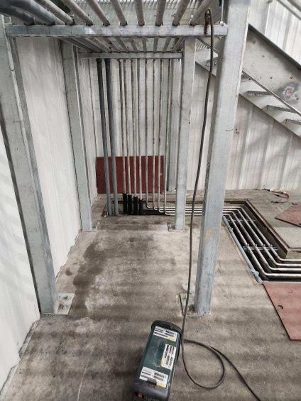 A machine is sitting on the floor in a room next to a staircase.