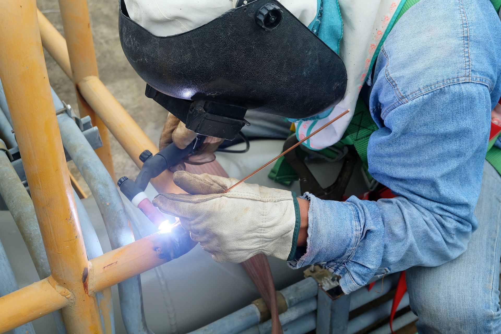 A man is welding a pipe with a welding machine.