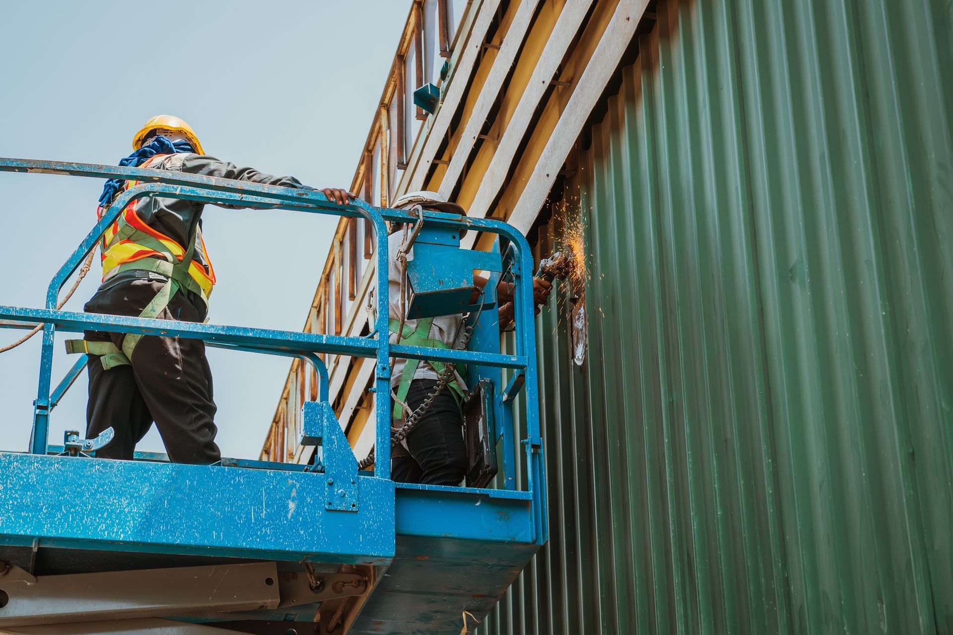 A man is standing on a lift working on a building.