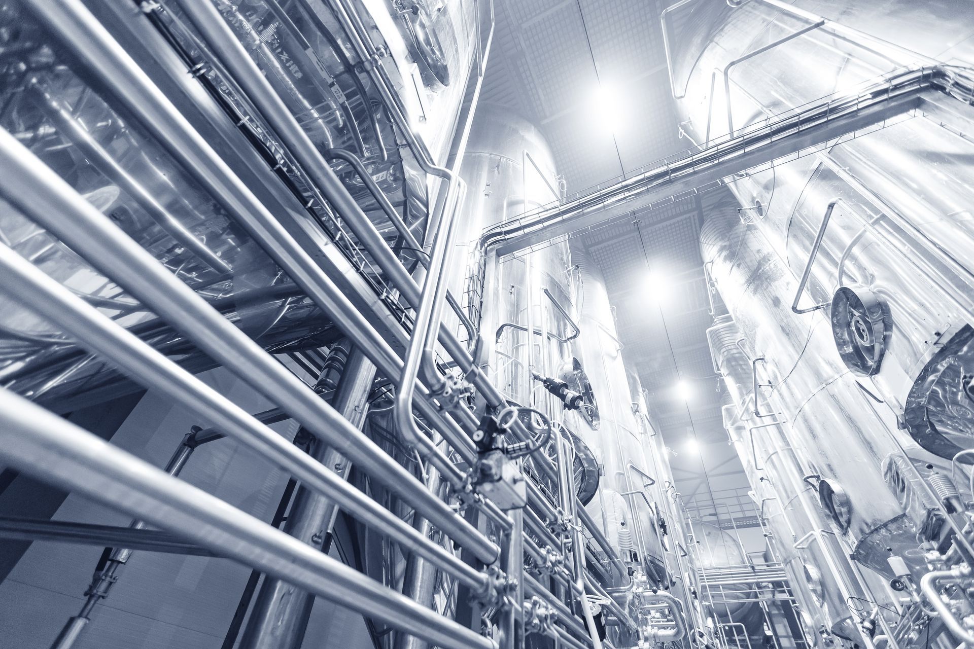 A black and white photo of a factory with lots of pipes.