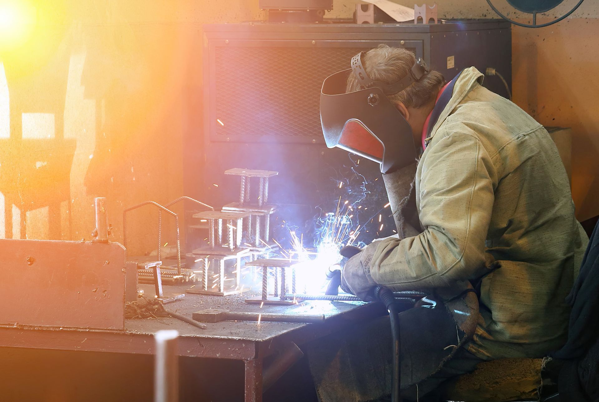 A man is welding a piece of metal in a factory.