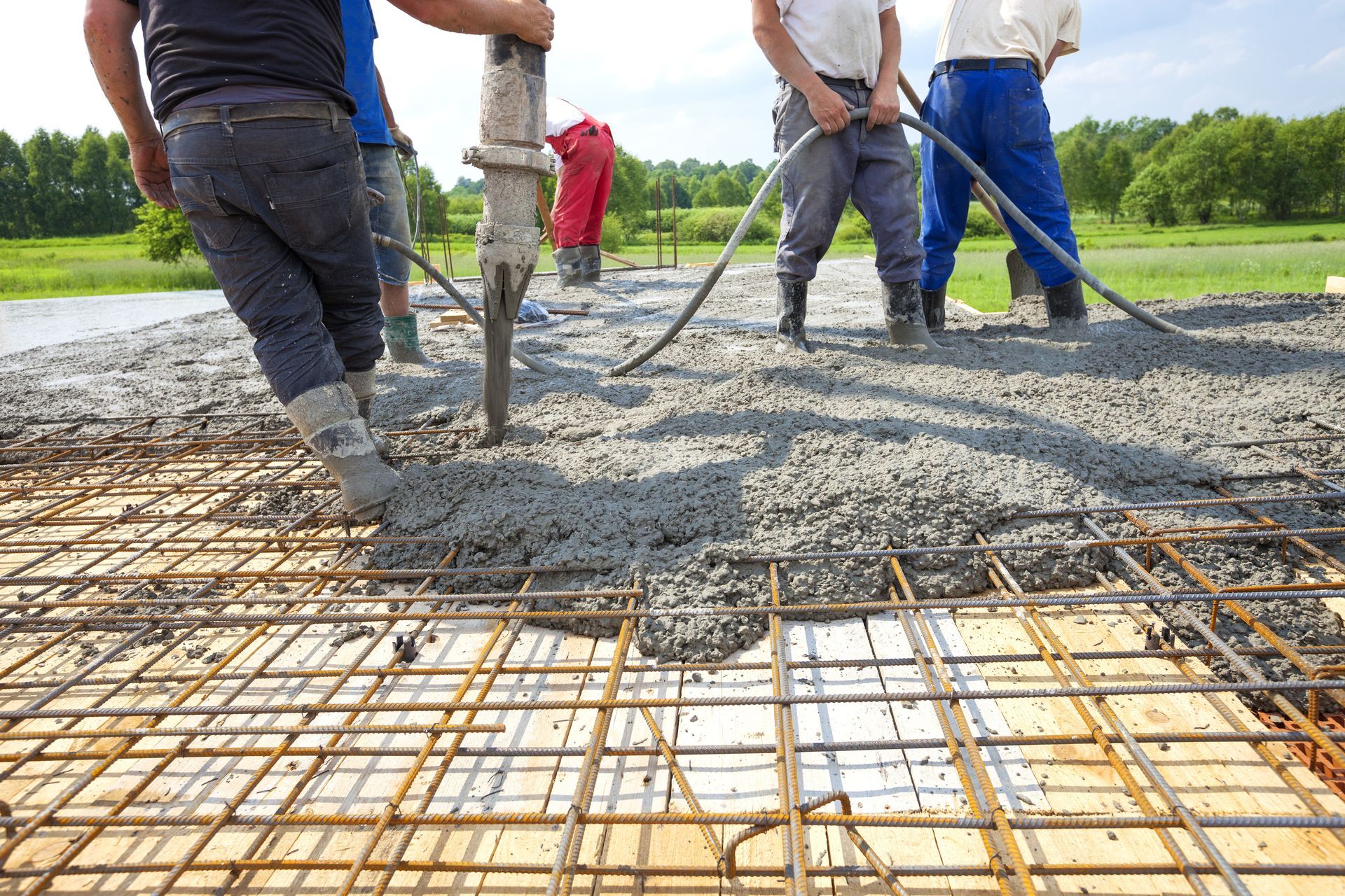 A group of construction workers are pouring concrete into a grid.