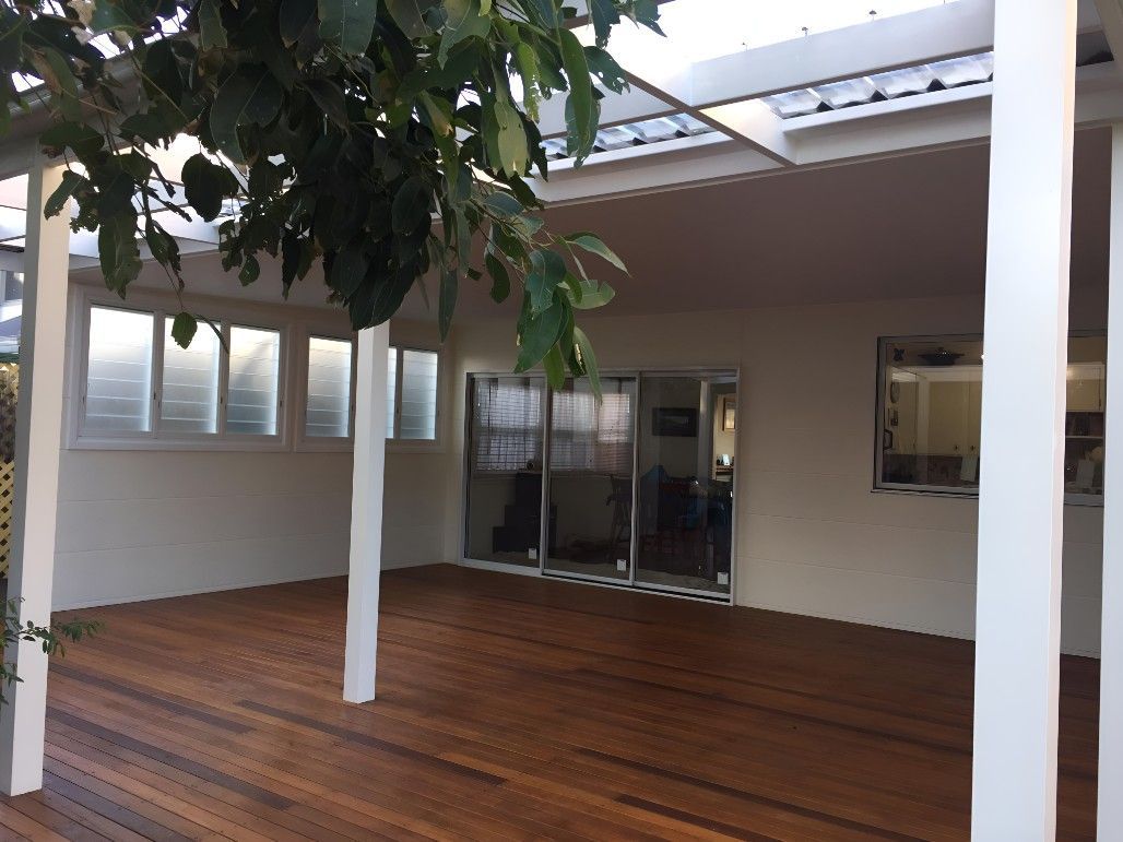 A Patio With a Wooden Deck and White Pillars — Let's Paint & Decorate Pty Ltd in Oak Flats, NSW