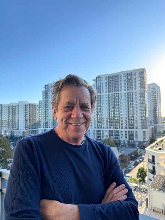 A woman is sitting at a desk with a laptop and a vase of flowers.