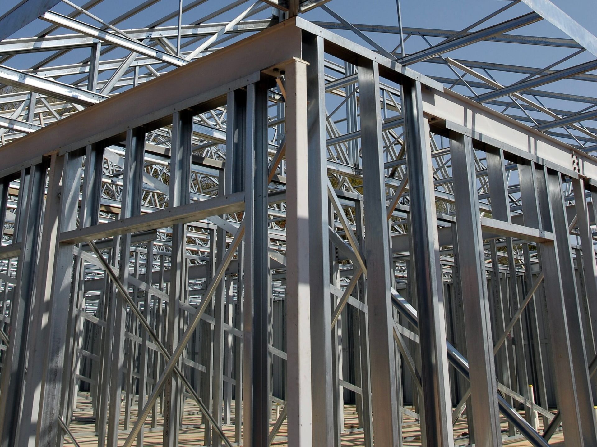 Steel frame of a building under construction, showing walls and roof supports.