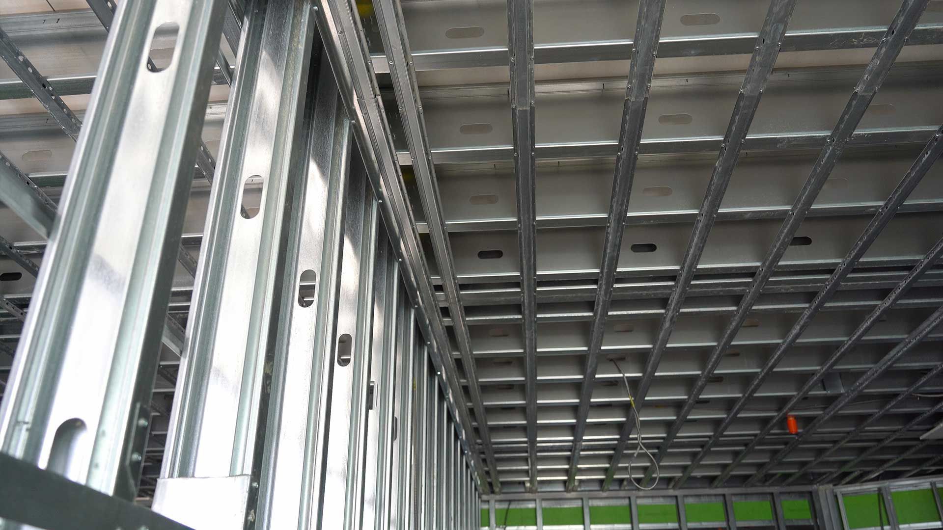 Metal framing of a building's interior, showing wall studs and grid ceiling supports.