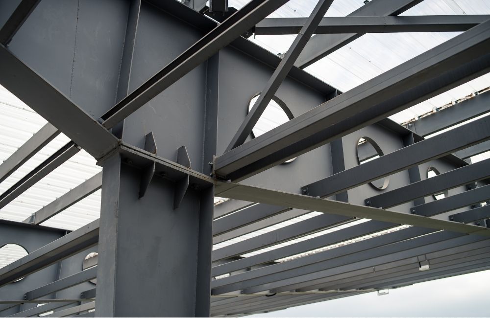 Person installing light brown siding on a building, using a hammer to nail it in.