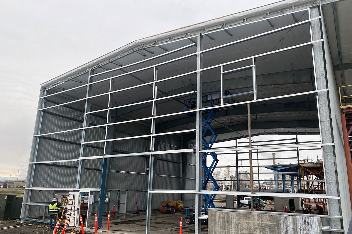Man on a ladder installing siding on a house, exterior wall, construction.