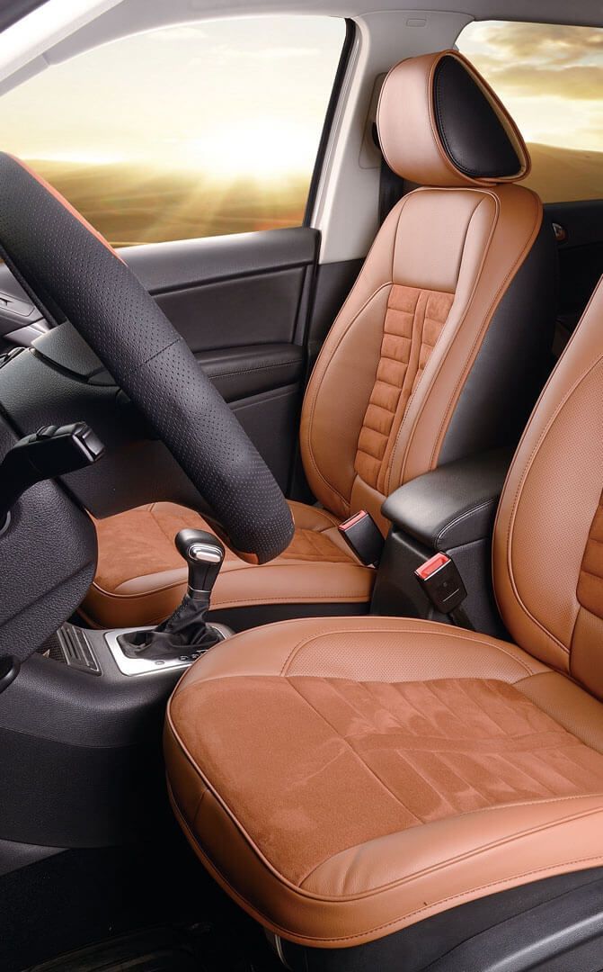 Car interior featuring tan and black leather seat covers, a matching steering wheel cover, and a gear shift.