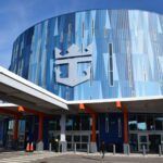 Modern cruise terminal entrance featuring blue reflective glass and a large Royal Caribbean crown logo.