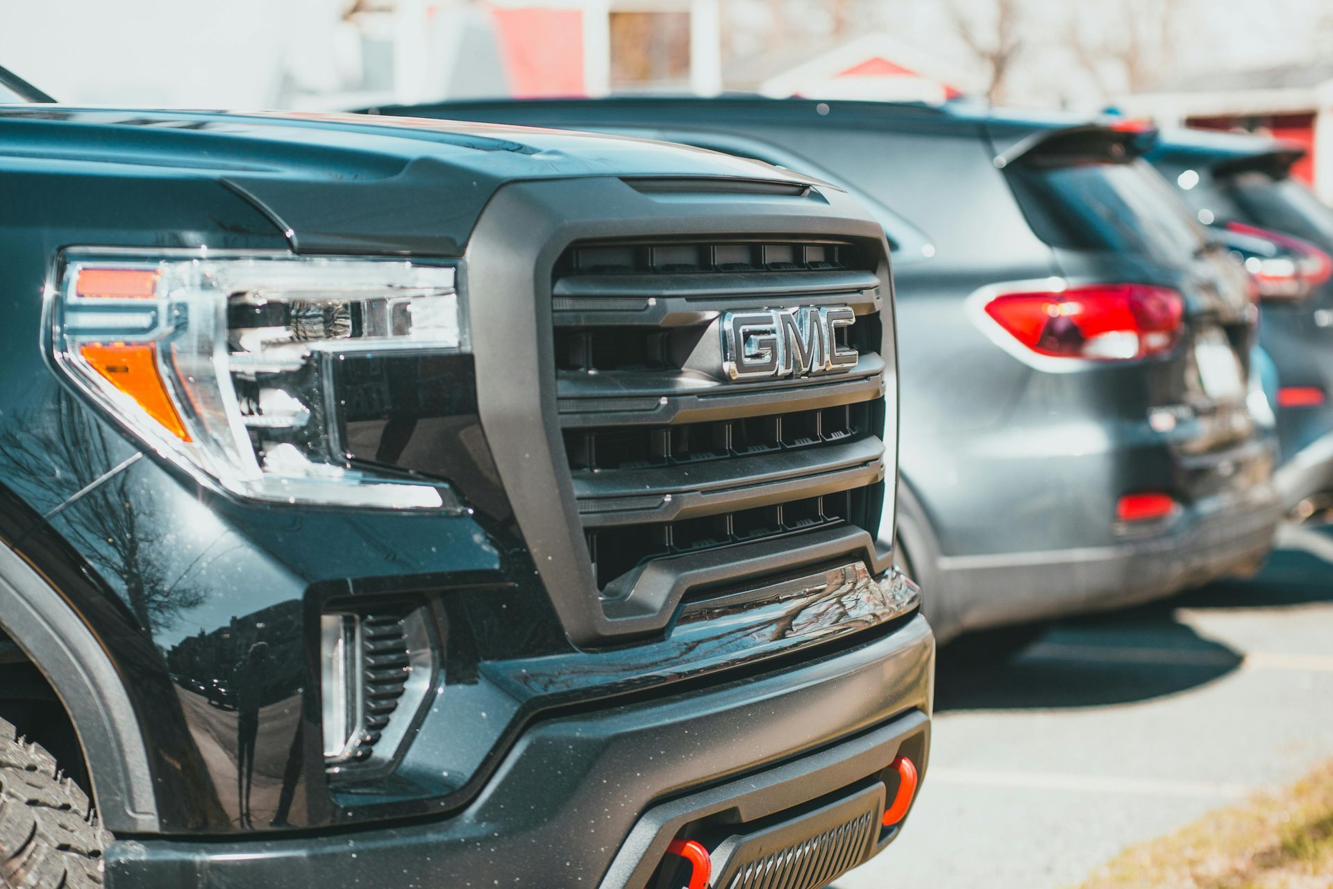 A close-up of a black GMC truck parked in a line of vehicles on a sunny day.