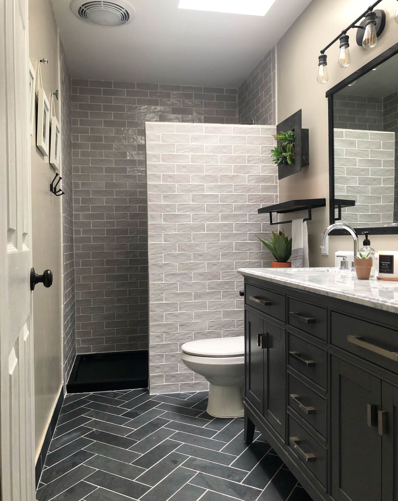 A bathroom with a toilet , sink , mirror and walk in shower.