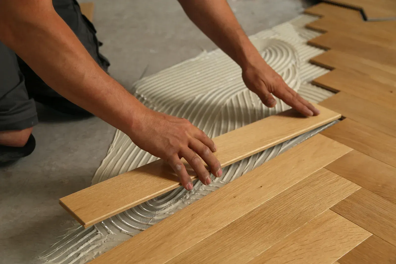 A person is laying a piece of wood on the floor