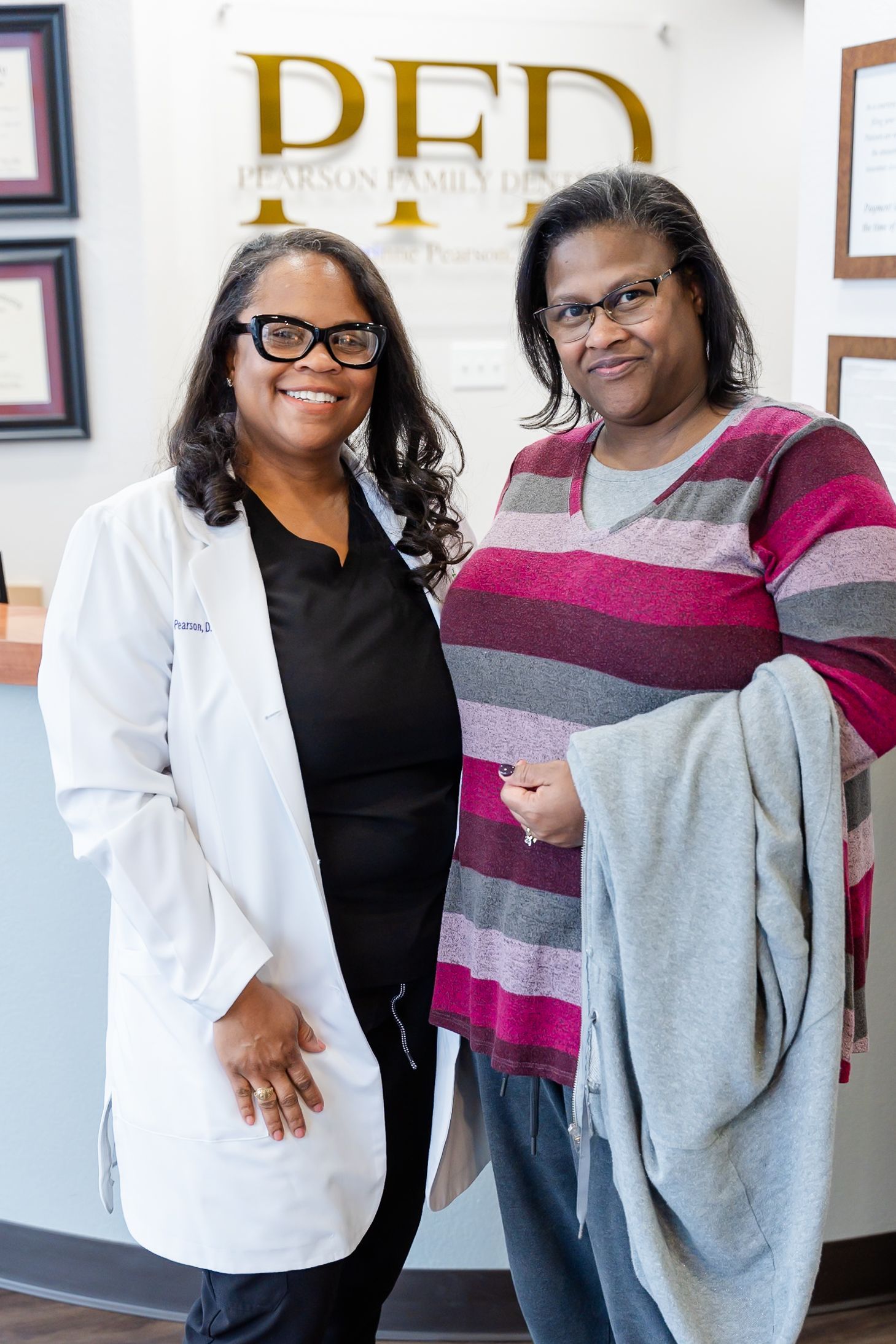 A woman is smiling while sitting in a dental chair.
