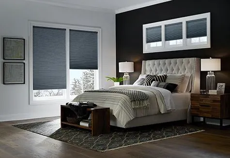 Modern gray bedroom with tufted bed, bedside lamps, windows, and patterned rug