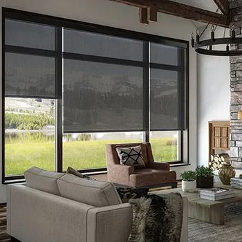 A living room with a couch , chair , coffee table and large windows.