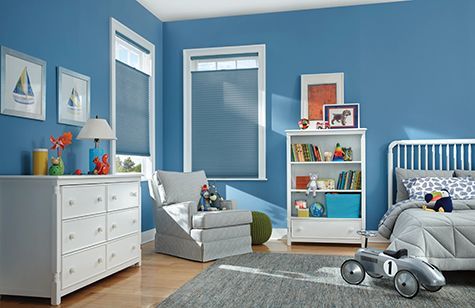 a child 's bedroom with blue walls , a bed , dresser , chair and toy car .