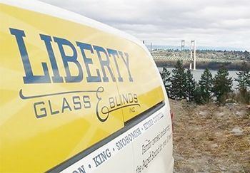 A yellow and white van that says liberty glass and blinds