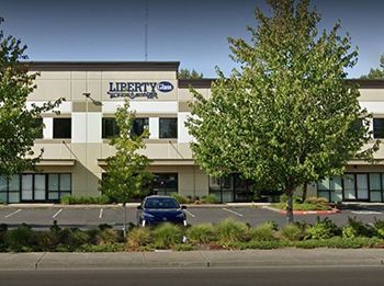 A large building with a blue car parked in front of it.