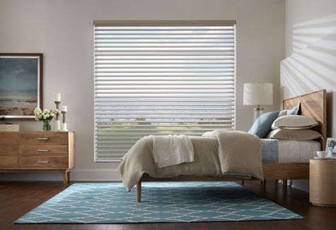 a bedroom with a bed , dresser , nightstand , rug and blinds .