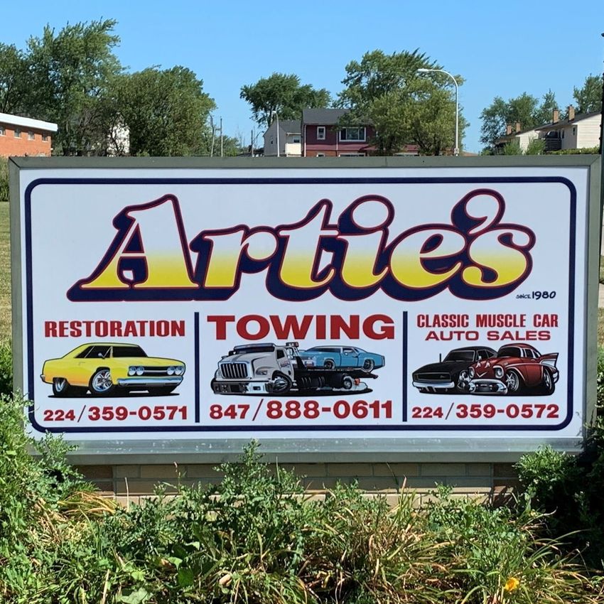 Sign for Artie's, offering restoration, towing, and classic car sales. Includes cars, phone numbers, and logos.