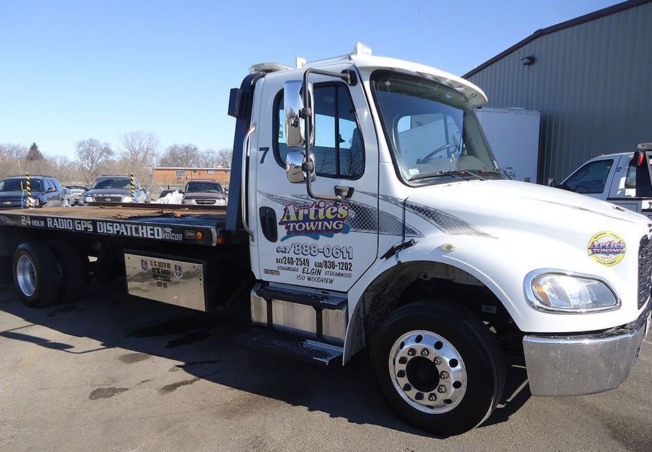 White Archer's Towing truck parked outside on a sunny day. The truck is white with black and gray details.