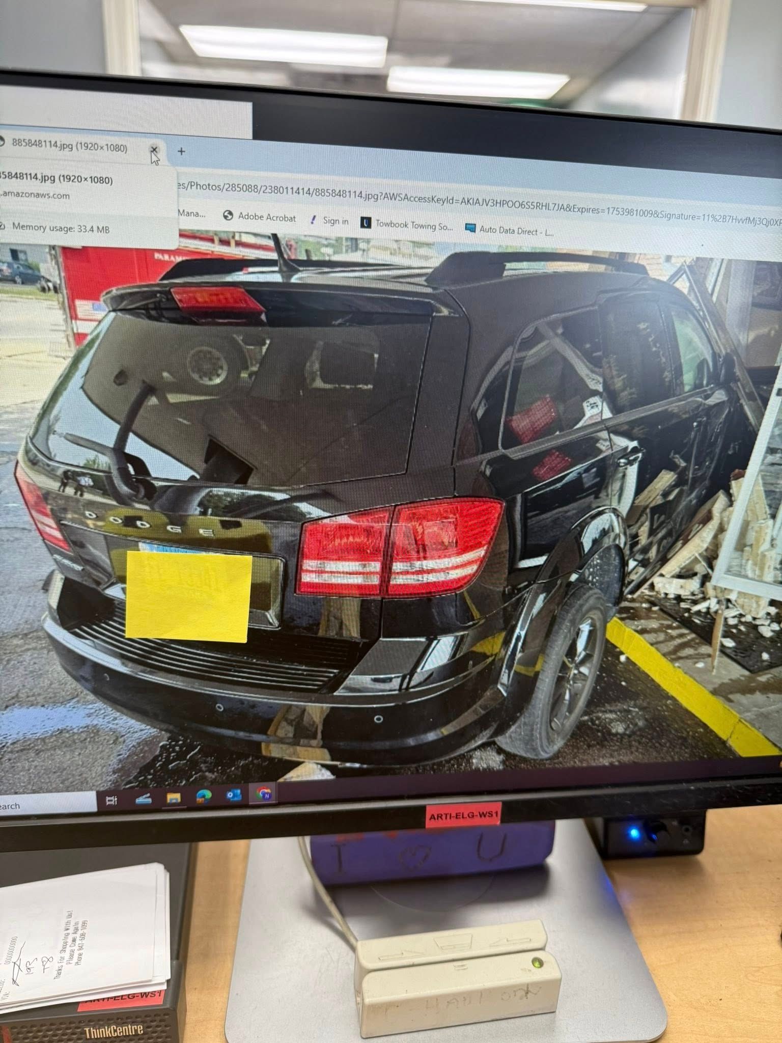 Black Dodge Journey SUV, rear view, parked in a yellow parking space with damage.