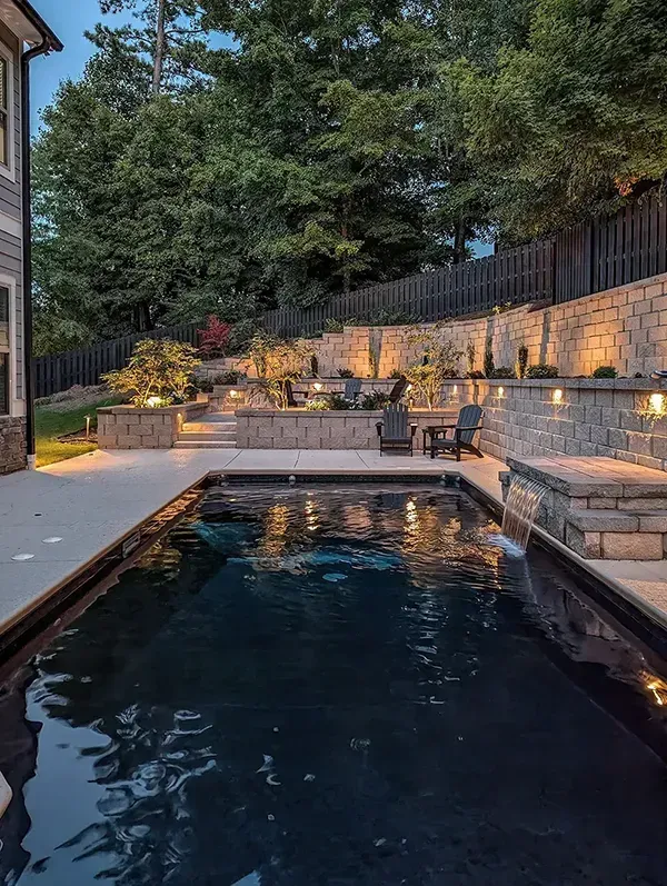 A large swimming pool is in the backyard of a house.