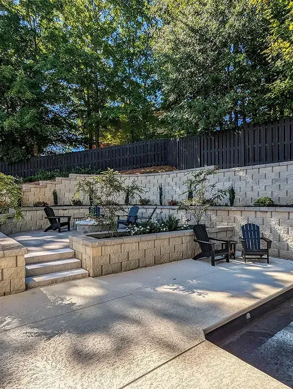 A patio with chairs and a fire pit next to a pool.
