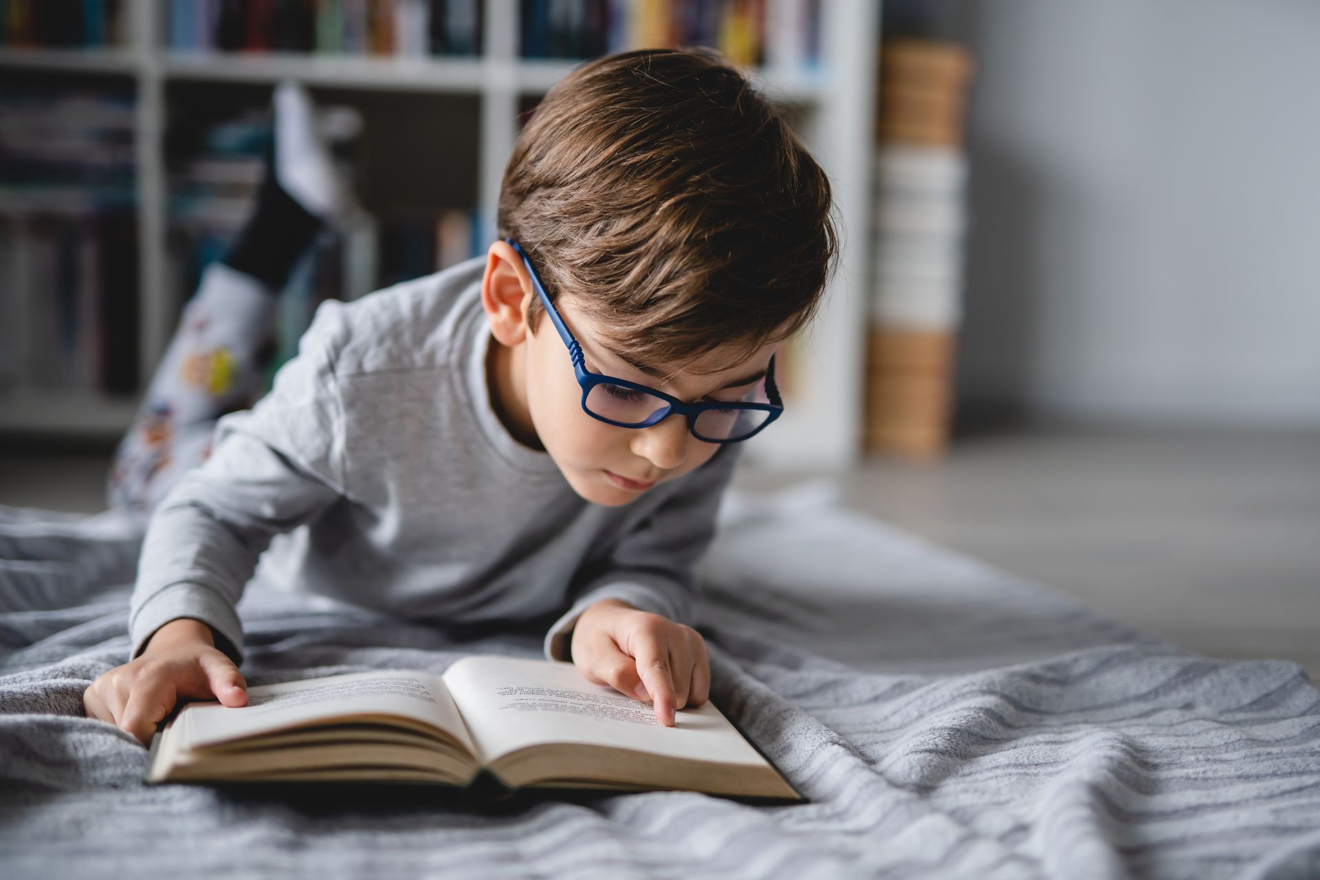 A boy with glasses is reading a book