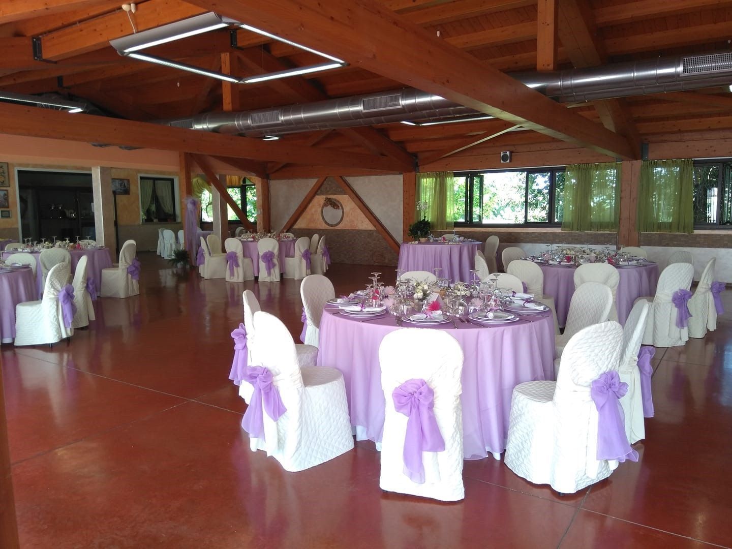 Una grande sala con tavoli e sedie allestita per un ricevimento di nozze