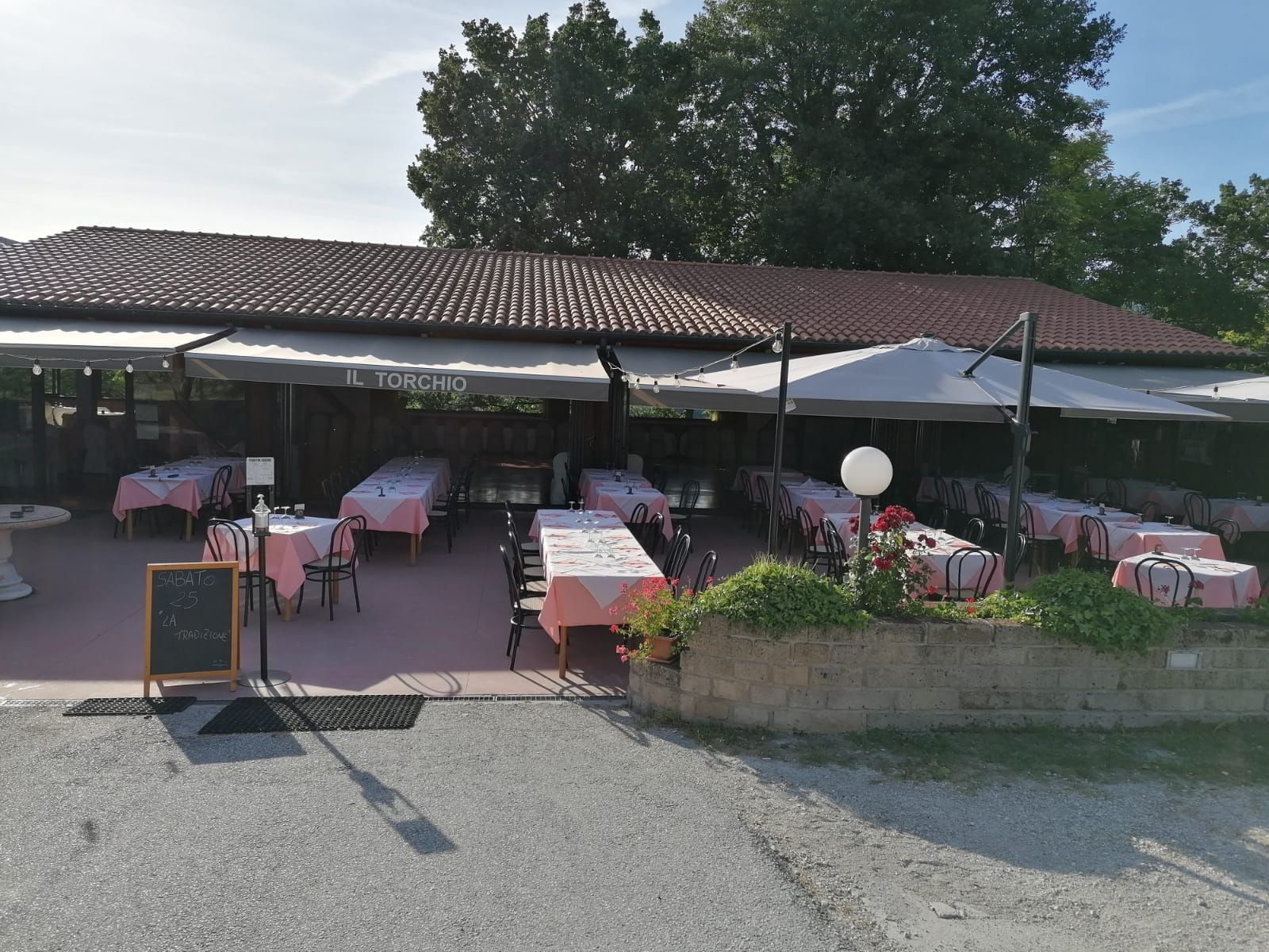 Un ristorante con tavoli e ombrelloni all'aperto in una giornata di sole