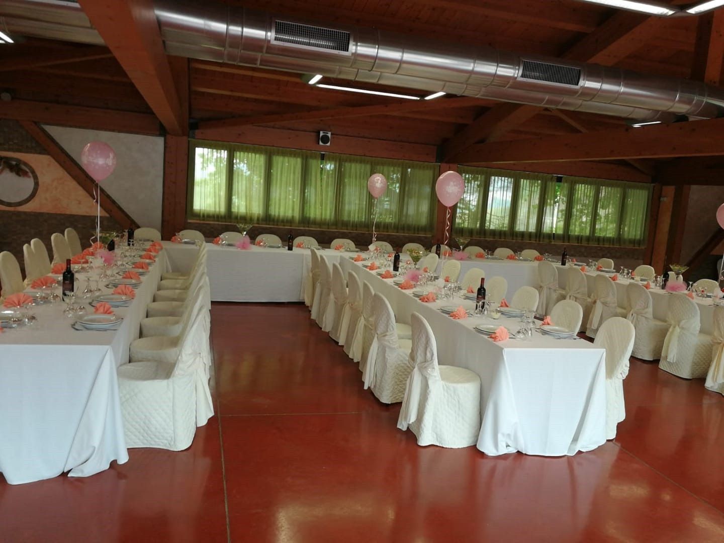 Una grande sala con tavoli e sedie allestita per un ricevimento di nozze