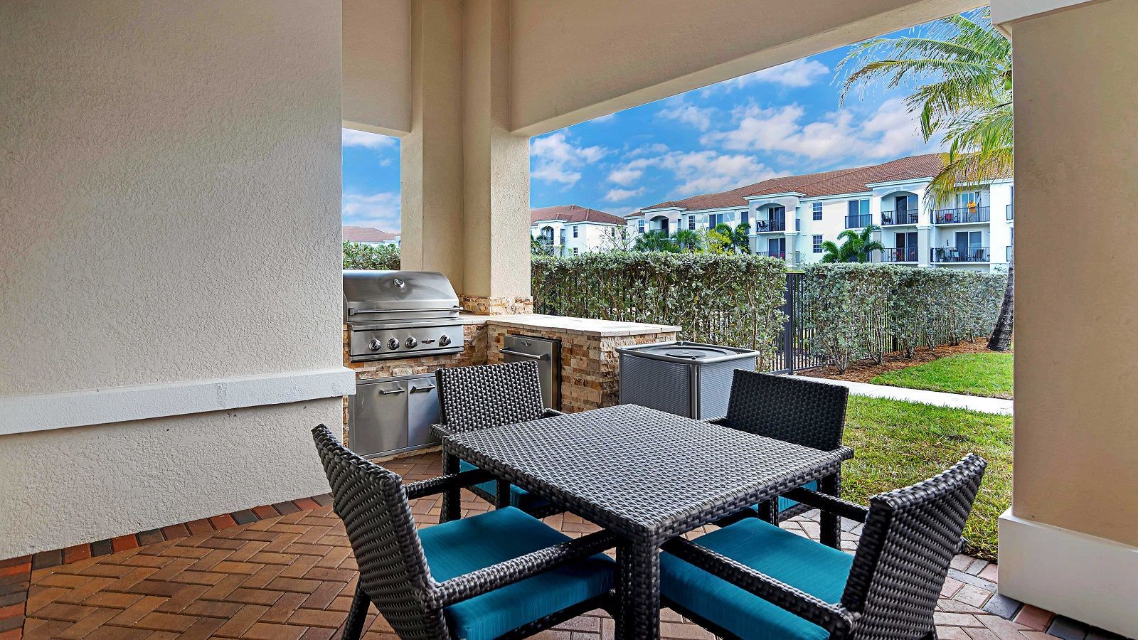 A patio with a table and chairs and a grill.