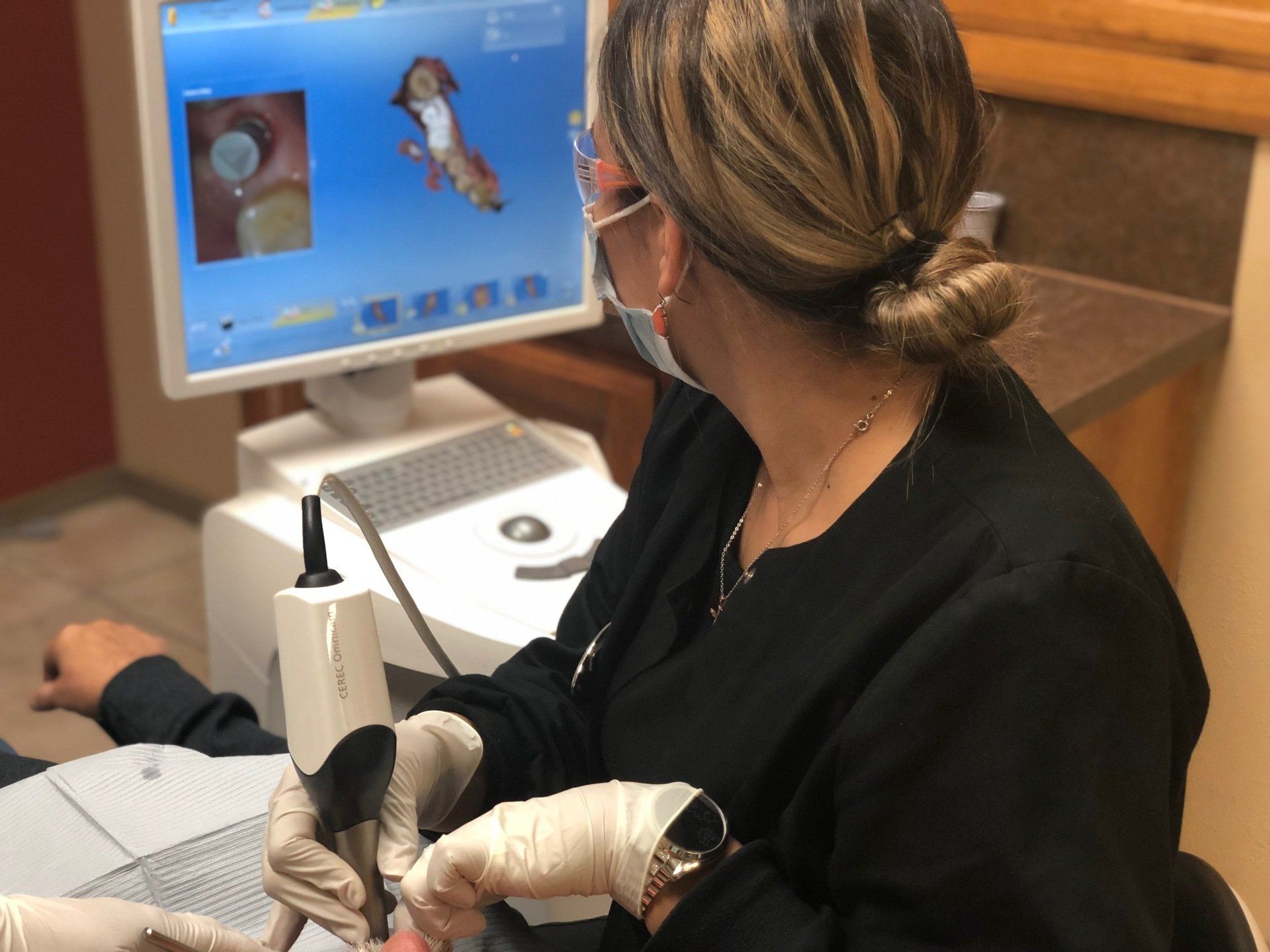 A woman wearing a mask is using a machine in front of a computer screen.