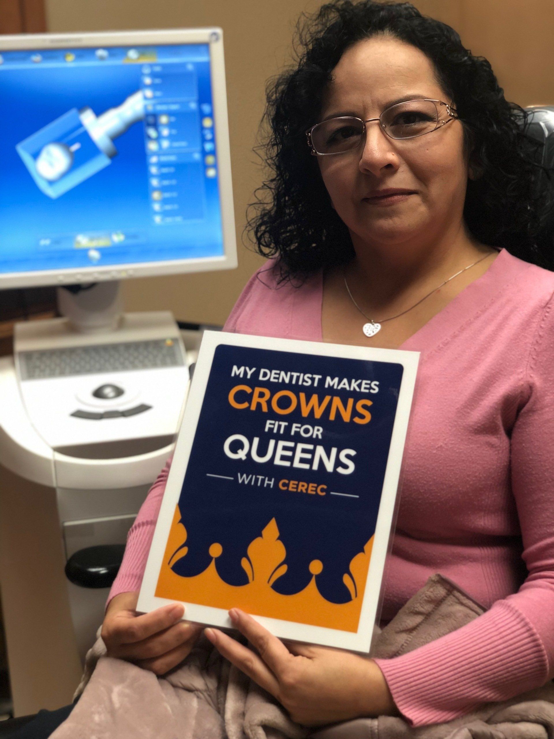 A woman holding a book that says my dentist makes crowns fit for queens