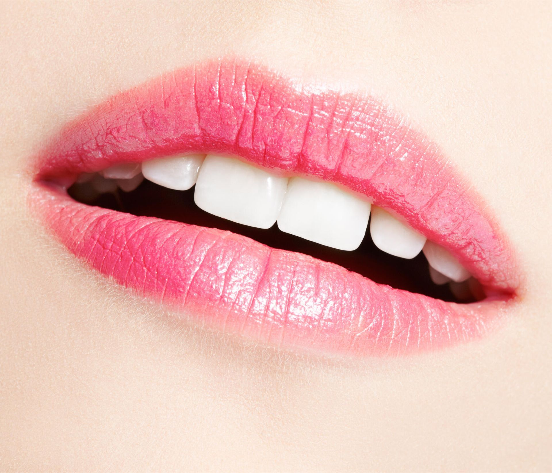 A close up of a woman 's lips with pink lipstick and white teeth