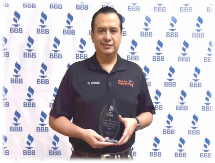 A man is holding a trophy in front of a wall that says bbb