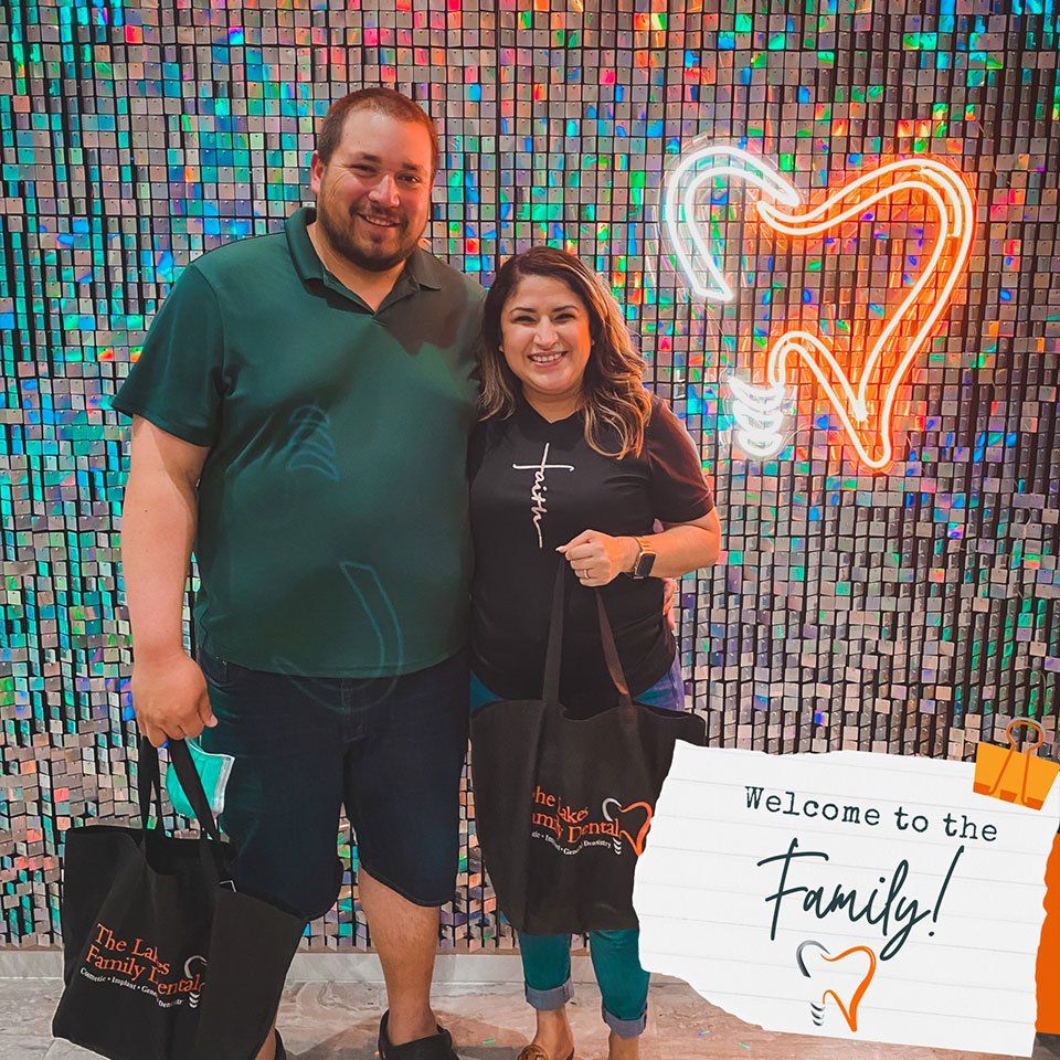 A man and a woman are standing in front of a sign that says welcome to the family.