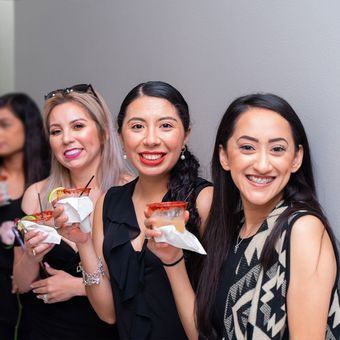 A group of women are standing next to each other holding drinks.