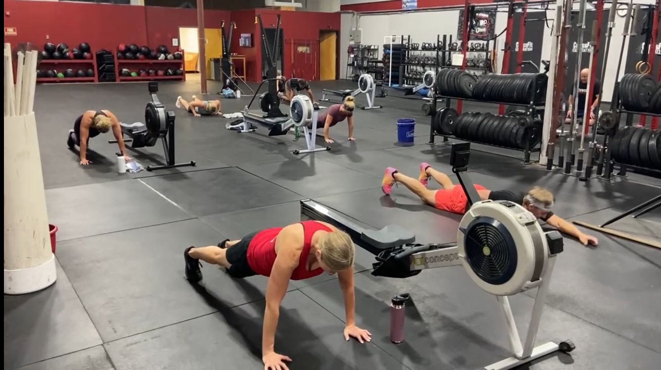 A group of people are doing push ups in a gym.
