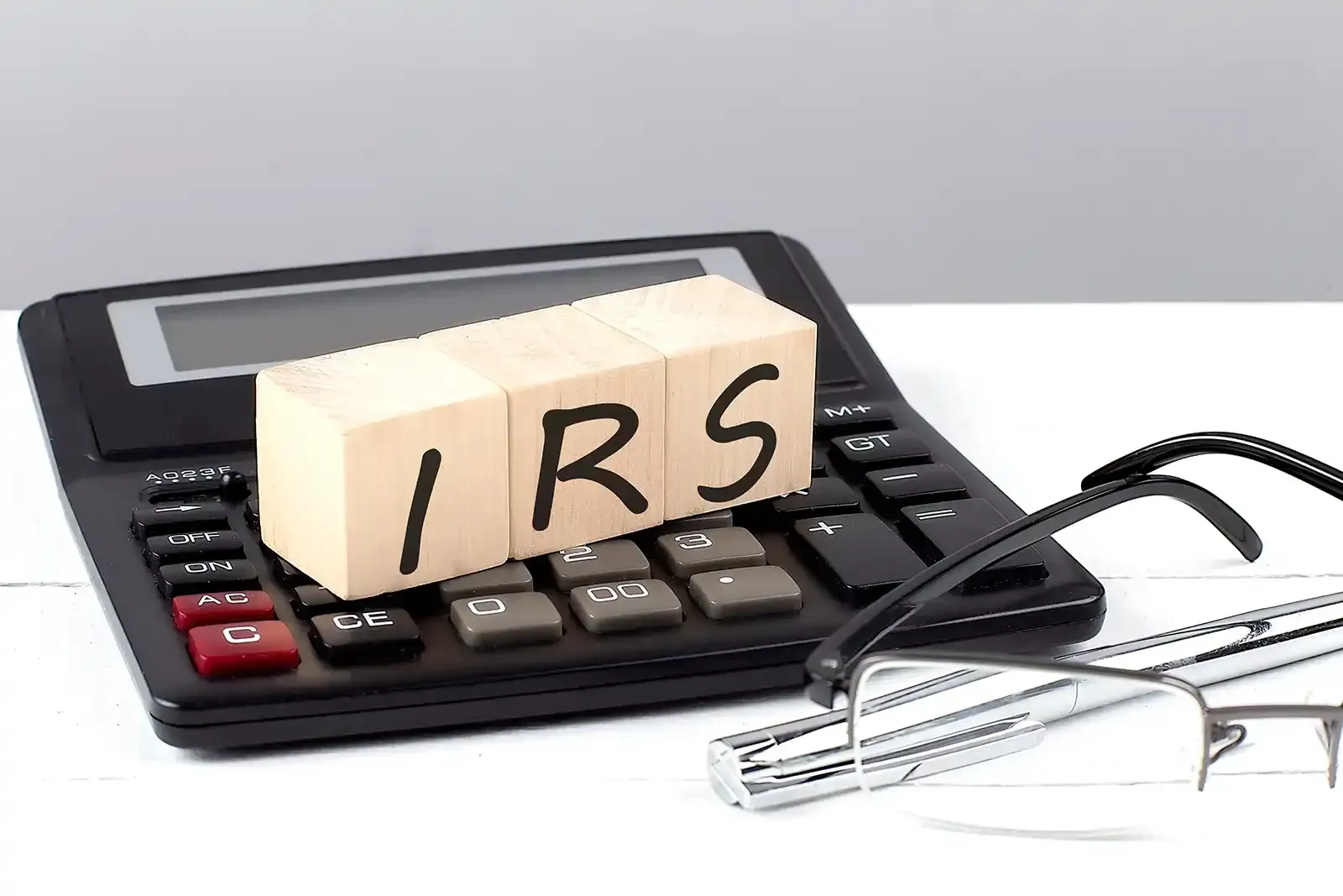 A calculator with a wooden block that says irs on it
