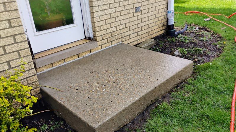 A concrete step is sitting in front of a brick house.
