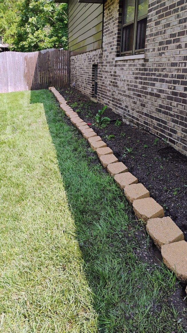 A brick walkway leading to a house next to a lush green lawn.