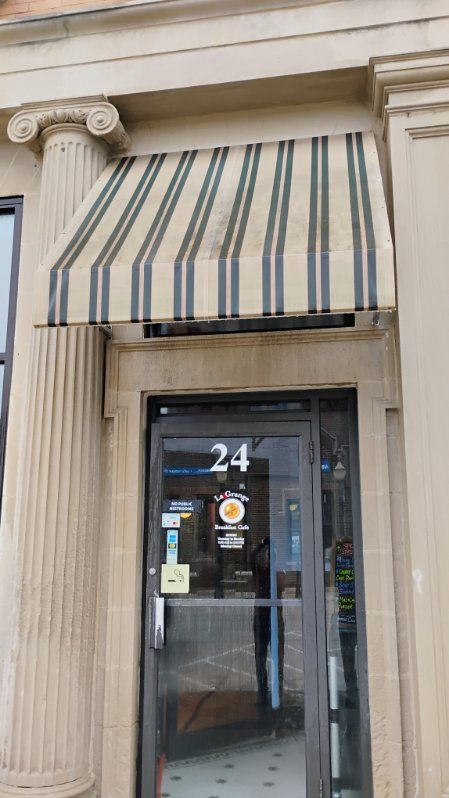 The front door of a building with a striped awning over it.