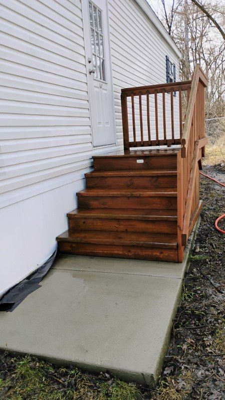 A wooden deck with stairs leading up to a white house.