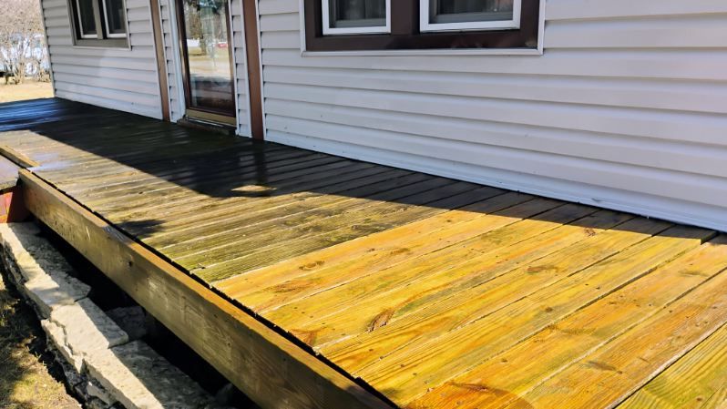 A wooden deck is sitting in front of a house.