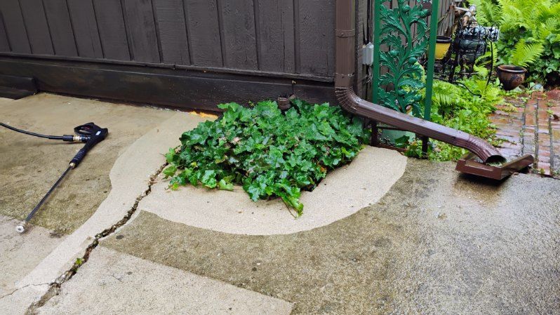 A pressure washer is being used to clean a concrete patio.
