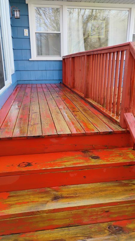 A wooden porch with red steps and a red railing.